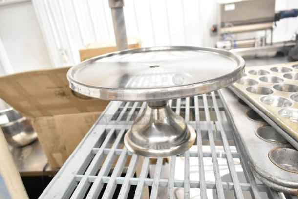 Stainless steel cake stand and muffin pans on metal rack; part of 38-item kitchenware set for auction.