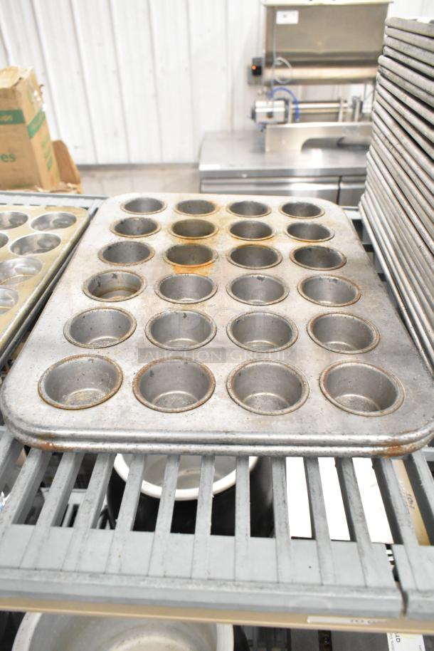 Metal muffin pans with 24 cups each, showing wear and discoloration, part of a 38-item kitchenware auction lot.