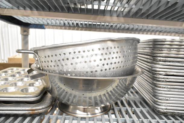 Set of 38 metal items including bowls, baking pans, muffin pans, and colanders in used condition, stacked on shelves.