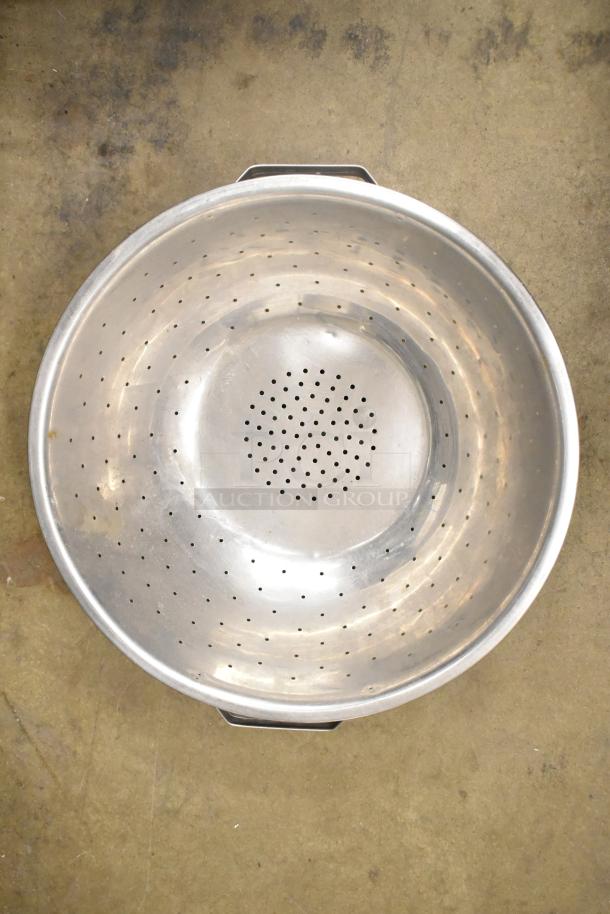 Stainless steel colander, perforated design, used condition, part of a 38-item kitchenware set including bowls and pans.