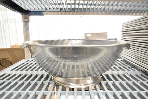Metal colander on industrial shelving, part of 38-item auction lot including bowls, baking pans, and muffin pans.