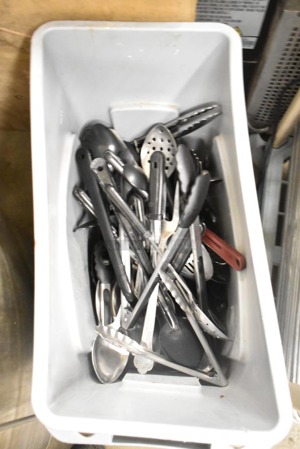 Rubbermaid Brute gray poly Slim Jim trash can with assorted tongs and serving spoons. Items in fair condition.