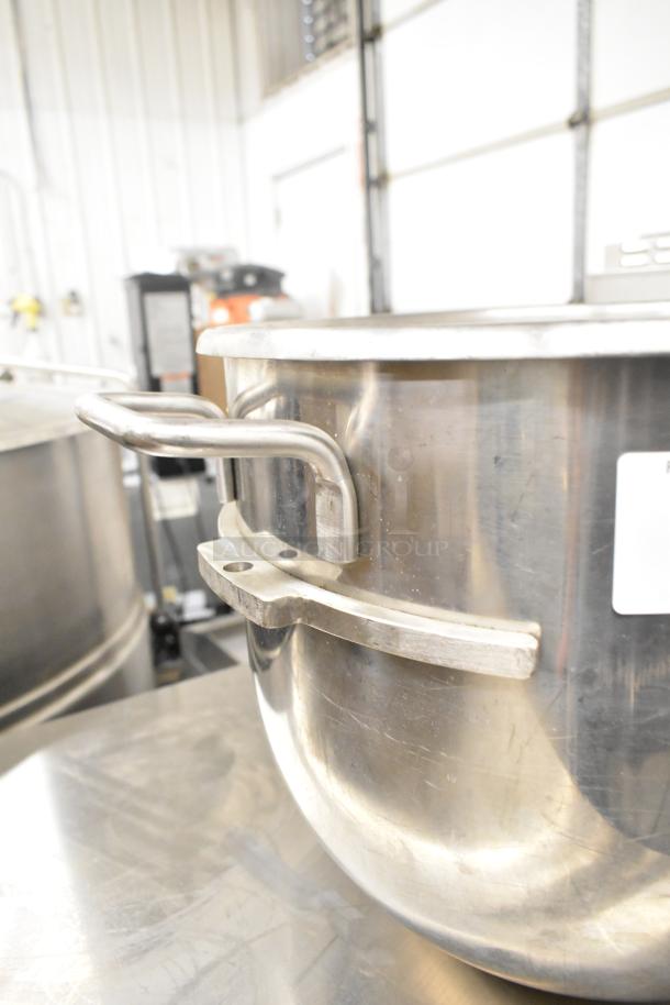 Stainless steel commercial mixing bowl with sturdy handles, minor surface wear, in good condition for auction.