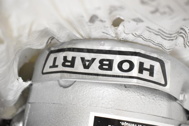 Hobart garbage disposal, silver finish, visible label. Compatible with 115/230/110/220 volts, 1 phase.