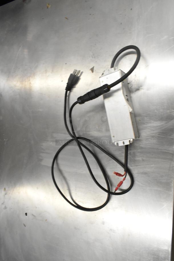 Mean Well MW HLG-80H-15A power supply, in used condition, with visible cables and connectors on a metallic surface.