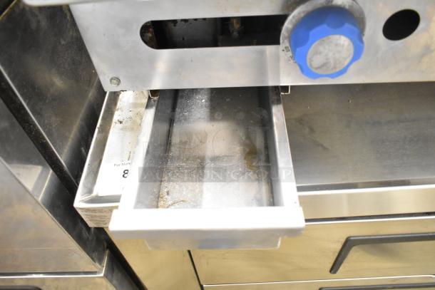 Imperial Commercial Gas Flat Top Griddle, stainless steel with blue knob, shows signs of use, grease drawer open.