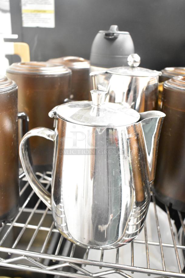 Various kitchen items including stainless steel coffee pots and black thermoses on a metal rack.