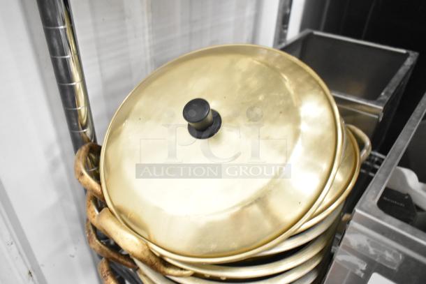 Stacked metal lids with black knobs and worn handles next to stainless steel bins on a storage shelf.