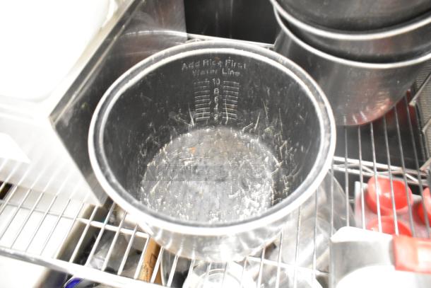 Auction item lot featuring drop-in bins, poly pitchers, cutting boards, and rice cooker inserts on a metal rack.