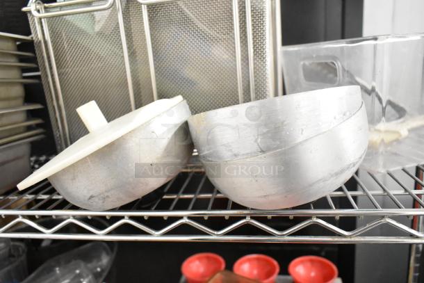 Assorted kitchen items on metal rack including bins, pitchers, cutting boards, rice cooker inserts, utensils. No shelving unit.