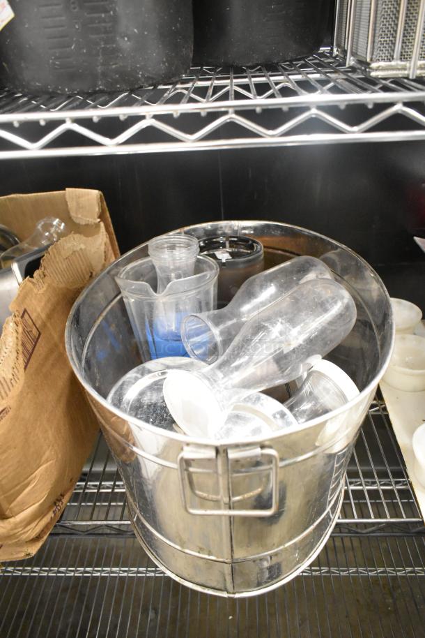 Variety of kitchen items in metal bin, including pitchers and rice cooker inserts. Cardboard box and black bins nearby. No shelving included.