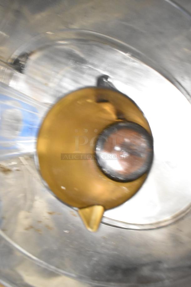 Blurry image showing part of a brown pitcher inside a metal container. Part of a mixed lot of kitchen items.