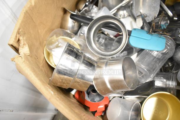 Assorted kitchen items including drop-in bins, poly pitchers, cutting boards, utensils, and rice cooker inserts in a cardboard box.