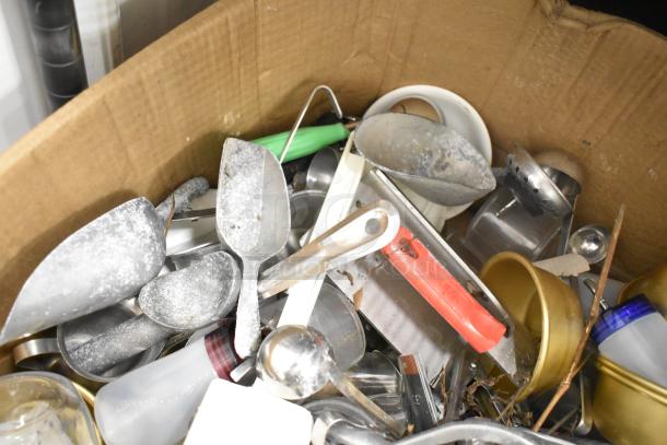 Assorted kitchen items in a box including scoops, pitcher, cutting board, rice cooker inserts, and utensils. No shelving included.