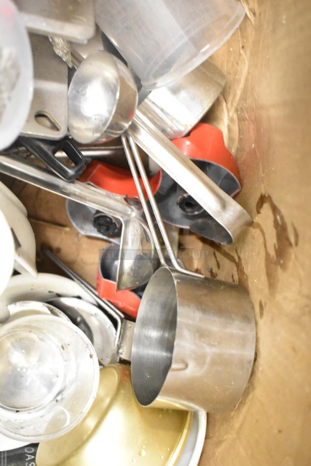 Assorted kitchen tools and accessories, including metal utensils, plastic bins, and pitchers in used condition.