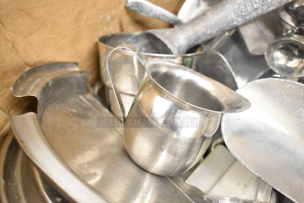 Assorted kitchen items including stainless steel pitchers, scoops, and utensil pieces in used condition.