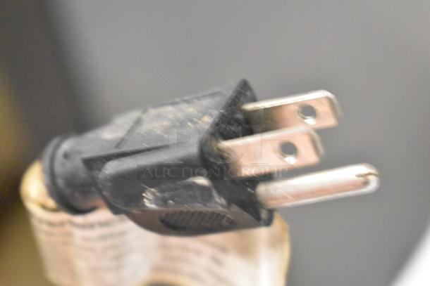 A close-up of a three-prong electrical plug connected to a wrapped coil on a Manitowoc ice machine.