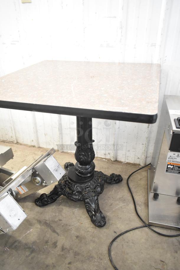 Dining height table with square faux marble top and ornate black cast iron pedestal base.