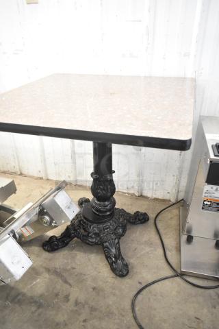 Dining height table with square faux marble top and ornate black cast iron pedestal base.