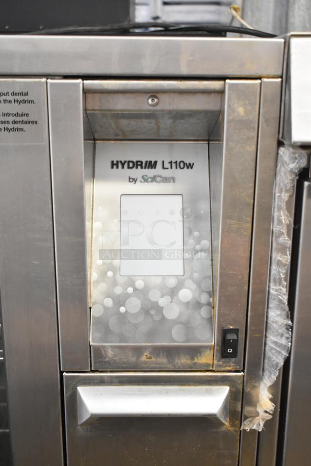 SciCan Hydrim L110W commercial washer, glass door, visible markings, stainless steel, signs of wear, automated cleaning.
