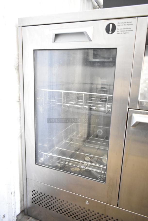 SciCan Hydrim L110W commercial automated washer with glass door, stainless steel finish, visible interior racks, in good condition.