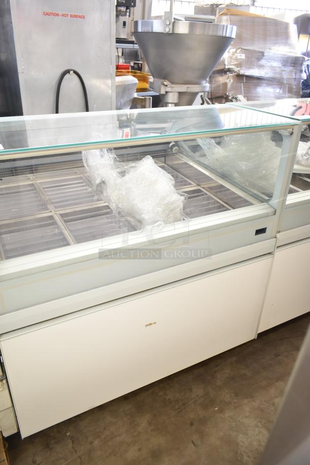 Commercial floor-style gelato display case merchandiser with glass top, multiple trays, and sturdy build, showing slight wear.