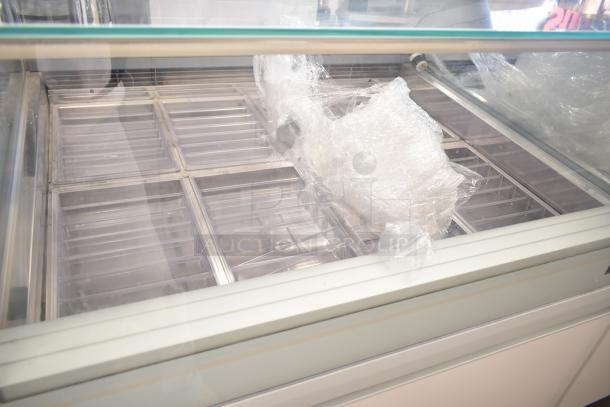 Commercial floor style gelato display case merchandiser with multiple compartments, glass front, and protective wrapping.