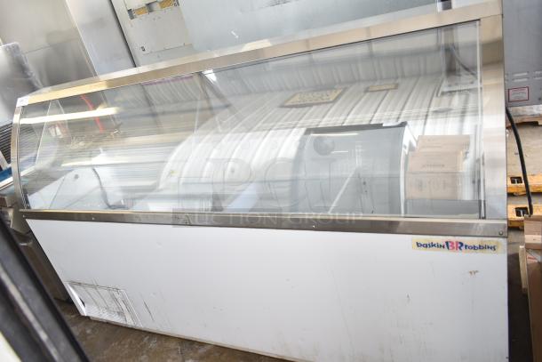 Commercial floor style ice cream dipping cabinet with glass top, visible wear, brand label present, spacious interior.