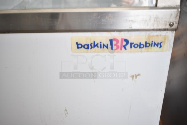 Commercial floor style ice cream dipping cabinet, Baskin Robbins branding, stainless steel edge, visible wear and scratches.