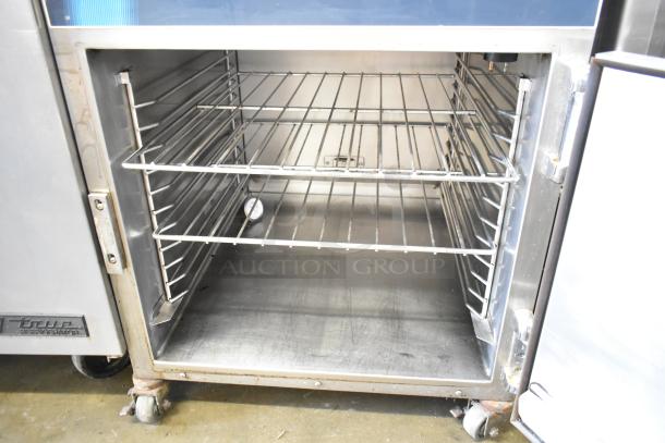Alto Shaam heated holding cabinet with commercial casters, featuring two shelves, stainless steel interior. Good condition.