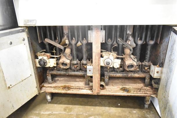 Pitco Frialator gas-powered deep fat fryer, floor style, visible wear and rust, temperature control knobs, label marked "Pitco Frialator."