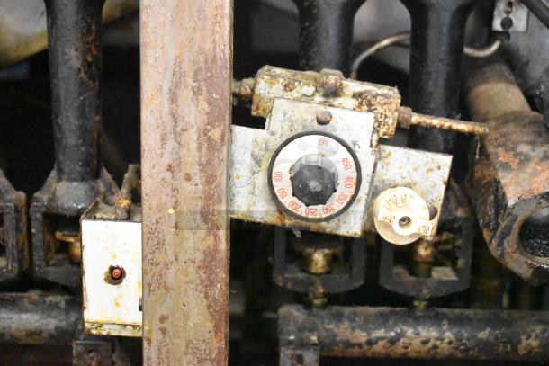 Pitco Frialator commercial gas fryer temperature controls, showing wear and rust. Off and pilot labels visible.