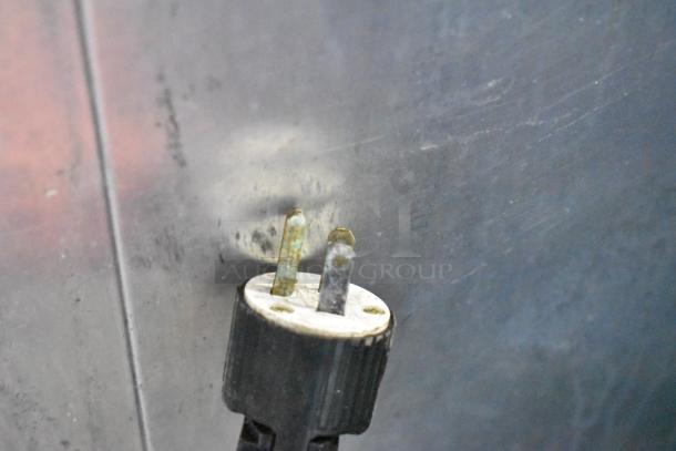 Close-up of a two-prong electrical plug from a True GDM-10 commercial cooler. Plug shows signs of wear.