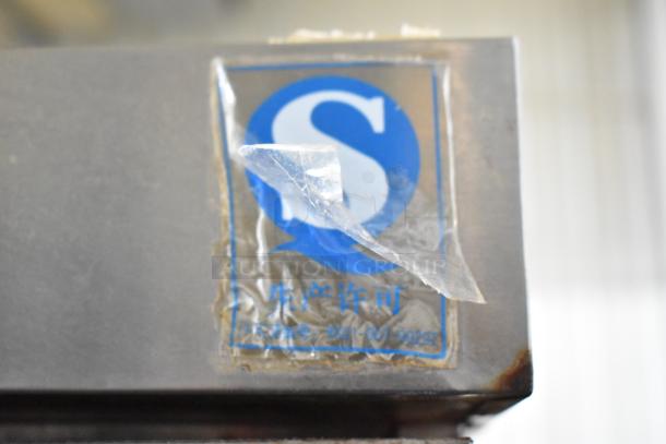 Alt text: Commercial Smoking Cabinet with peeling sticker showing a blue "S" logo and Chinese text. Rust visible on edges.