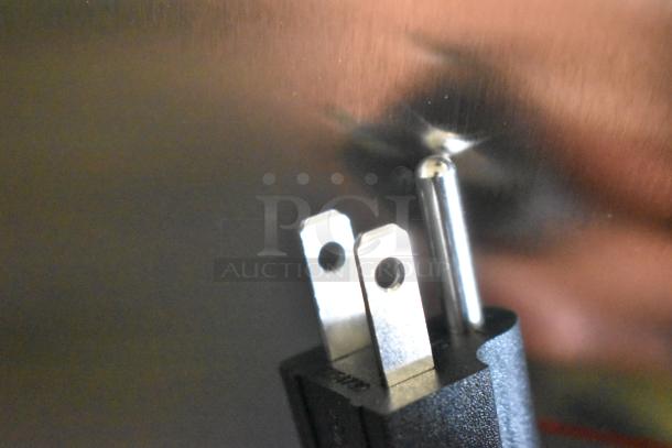 Close-up of a plug reflecting on a stainless steel surface, highlighting part of the Avantco 177CMA1B coffee maker.