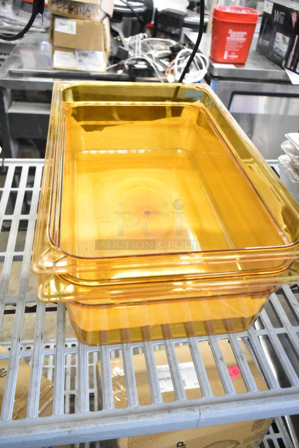 Stacked amber high-heat plastic food pans on a metal rack, showcasing Carlisle 10402B13, 6 inches deep, brand new condition.