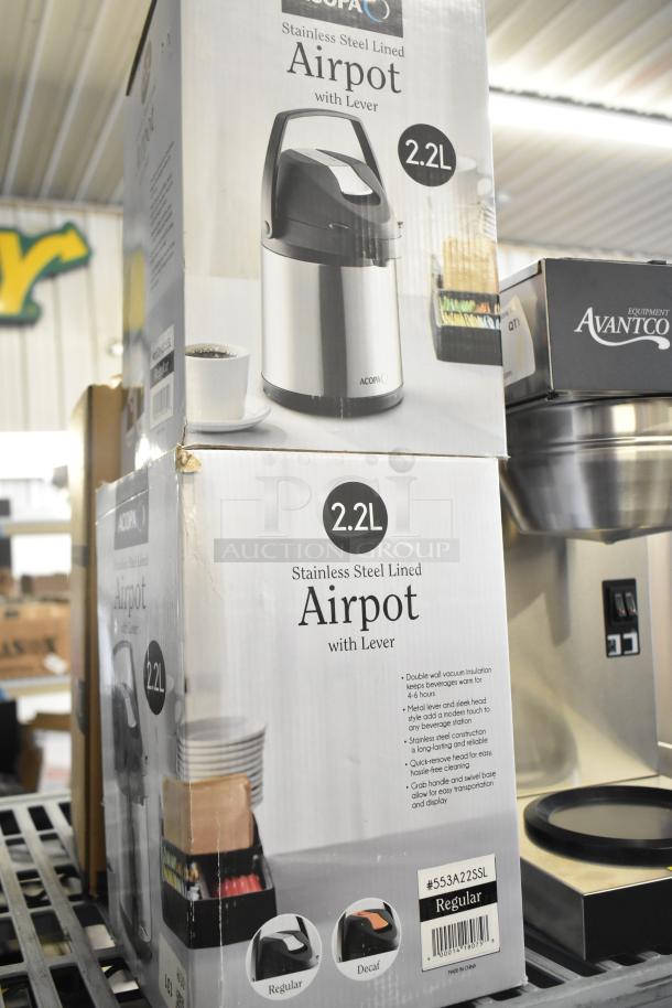 Five brand new airpots, including Avantco and Acopa models, all stainless steel lined with levers; shown with packaging.