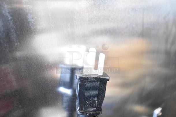 Close-up of a 115-volt plug for the Avantco 177HPI1836 heated holding cabinet, reflecting on a stainless steel surface.