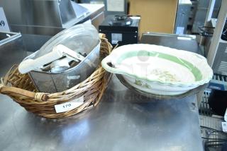 Wicker basket holding a metal wire basket, mandolin slicer, and a ceramic dish with green trim, auction lot tag marked "170".