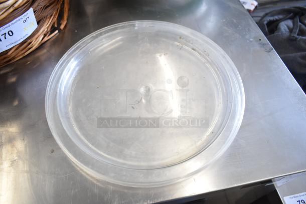 Alt text: Clear plastic dish lid, lightly scratched, on a metal surface near a woven basket with auction tag number 70.