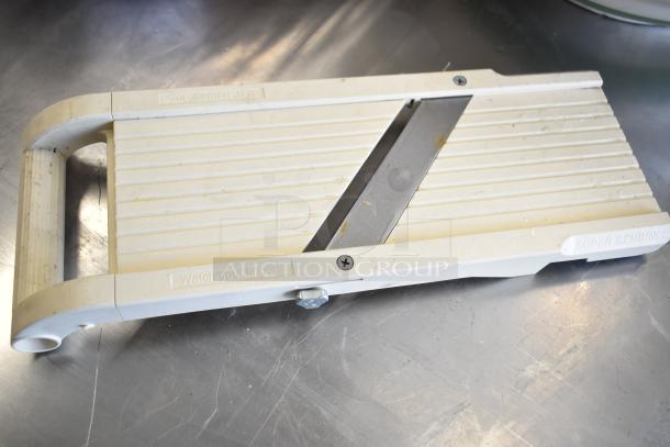 Super Benriner mandolin slicer in used condition. Features ribbed surface, adjustable blade, and safety warning.