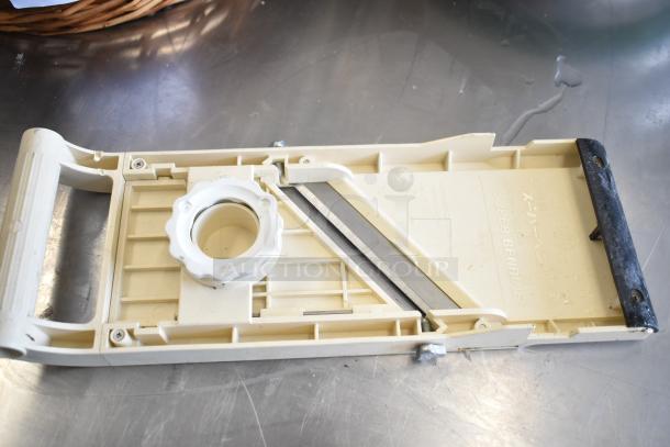 Plastic mandolin slicer on metal surface, "Super Benriner" label visible, includes adjustable blade and ergonomic handle.