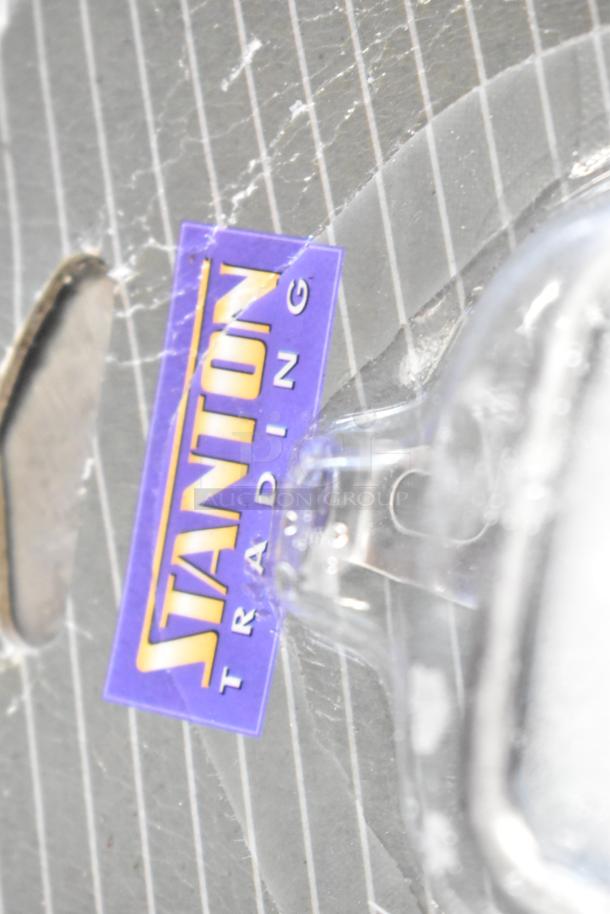 Close-up of a Stanton Trading label on a scratched surface, part of a set of various items for auction.