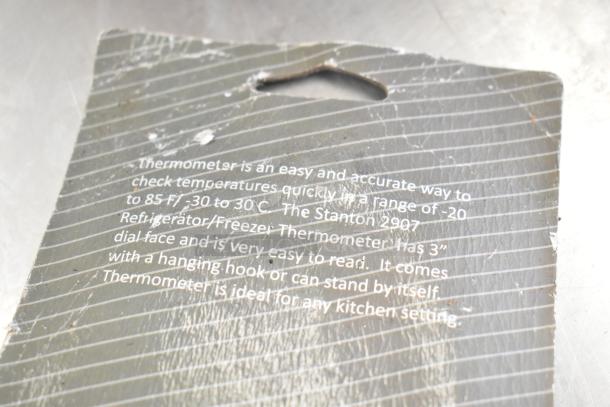 Worn packaging tag detailing a thermometer's features, range -20 to 85°F, 3" dial, hanging hook, easy read for kitchen use.