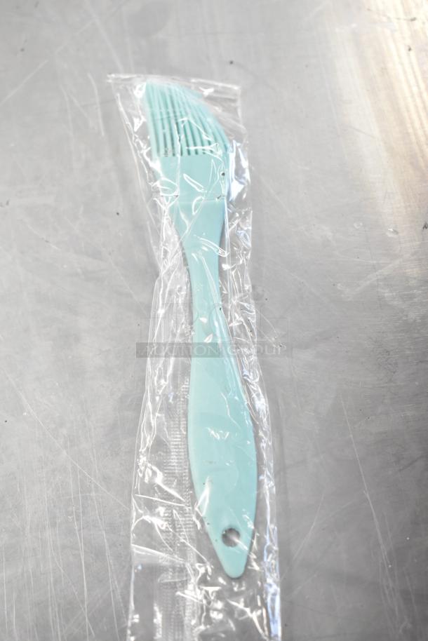 Aquamarine basting brush in clear packaging, new condition. Part of auction lot with five other kitchen items.