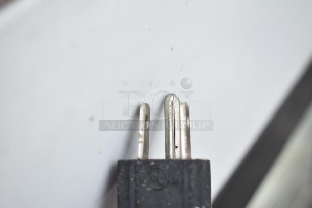 Close-up of a three-pronged electrical plug for a Torrey TEM150+ deli display case, showing slight wear.