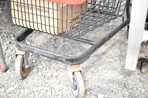 2 tier shopping cart with black metal frame, visible wear on wheels, containing a box labeled "MN Receipt Printer."