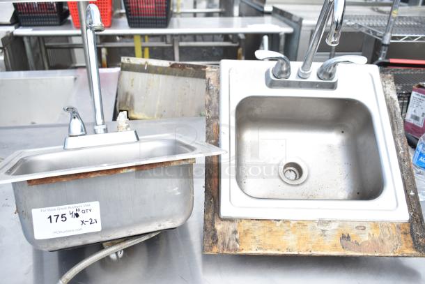 Two single bay drop-in sinks, stainless steel, with faucets, visible surface rust and wear, auction item label attached.