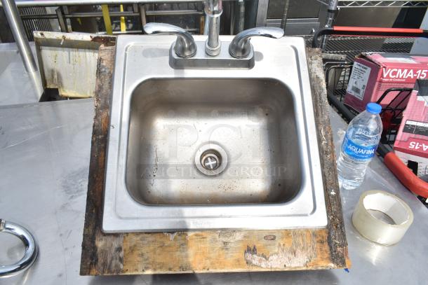 Two single bay drop-in stainless steel sinks with faucets; visible rust and wear on edges.