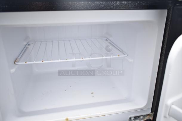 Interior of a mini cooler with a wire shelf, showcasing capacity and condition. Model details: Magic Chef HMDR450BE.